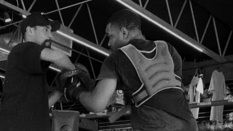 Boxing coach doing mitt work with athlete in boxing ring
