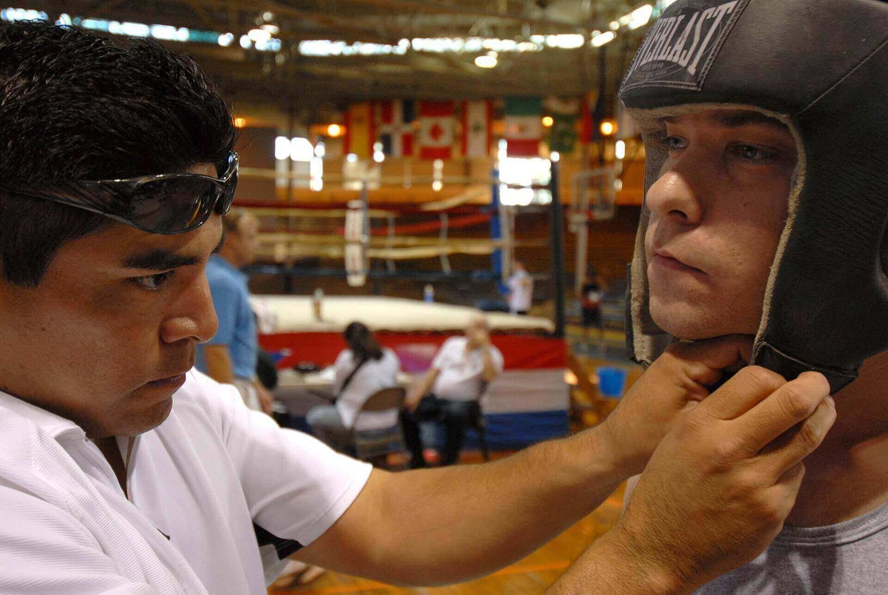 A trainer fixing the headgear of the boxer