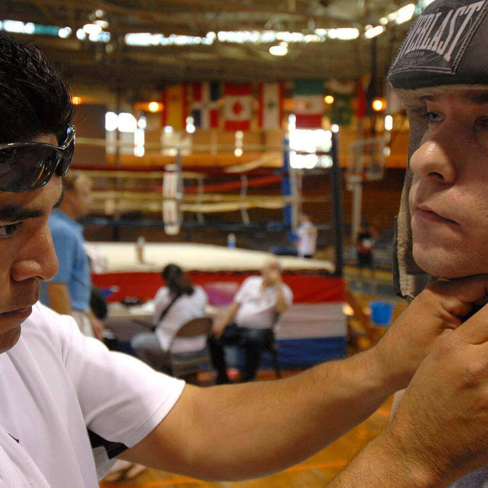 A trainer fixing the headgear of the boxer