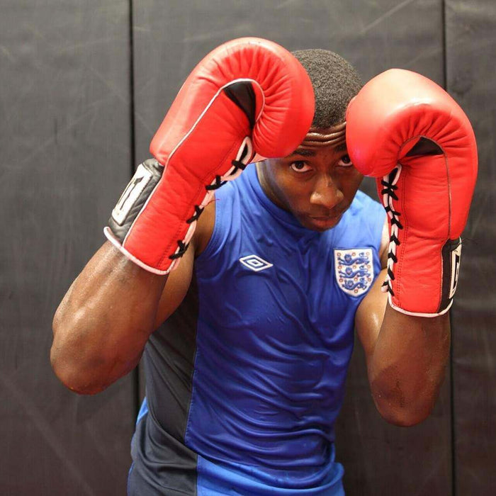 Boxer in a defensive guard stance wearing red boxing gloves.