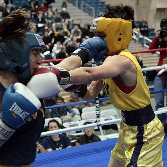 Two female boxers sparring in a boxing ring during a championship match