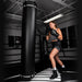 Person in boxing attire standing next to a punching bag in a gym setting