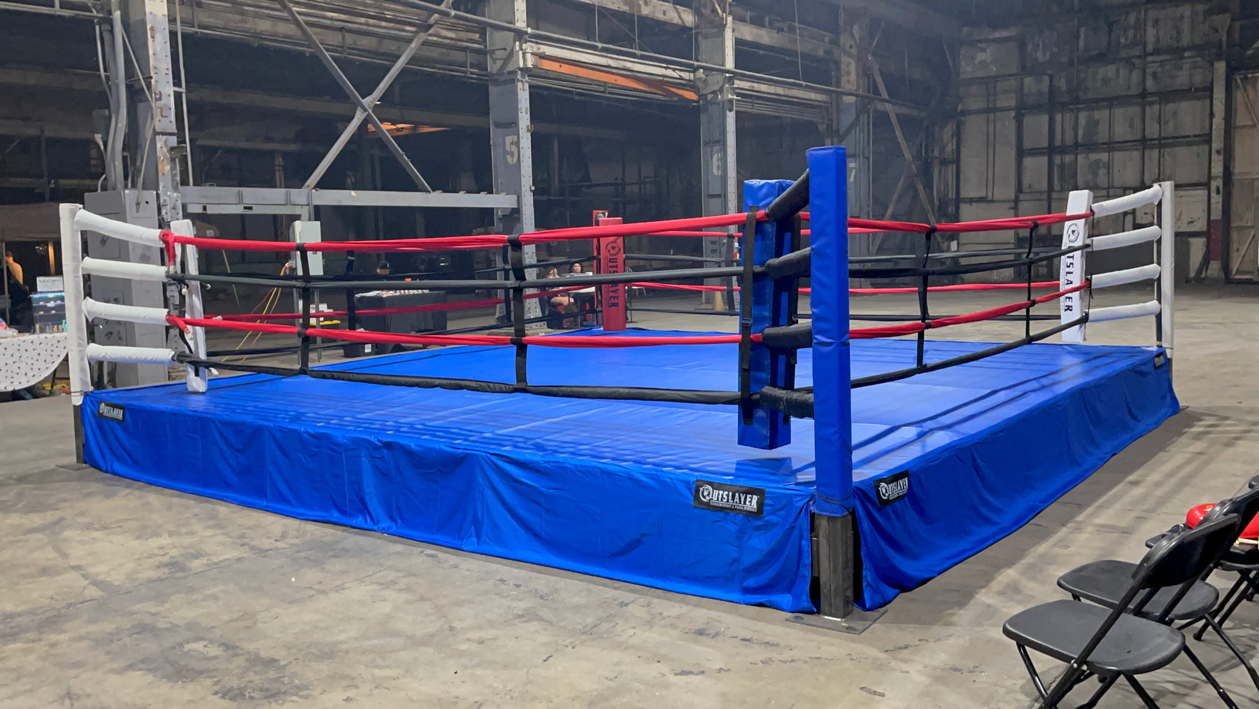 Boxing ring with blue mat and red ropes in an indoor setting