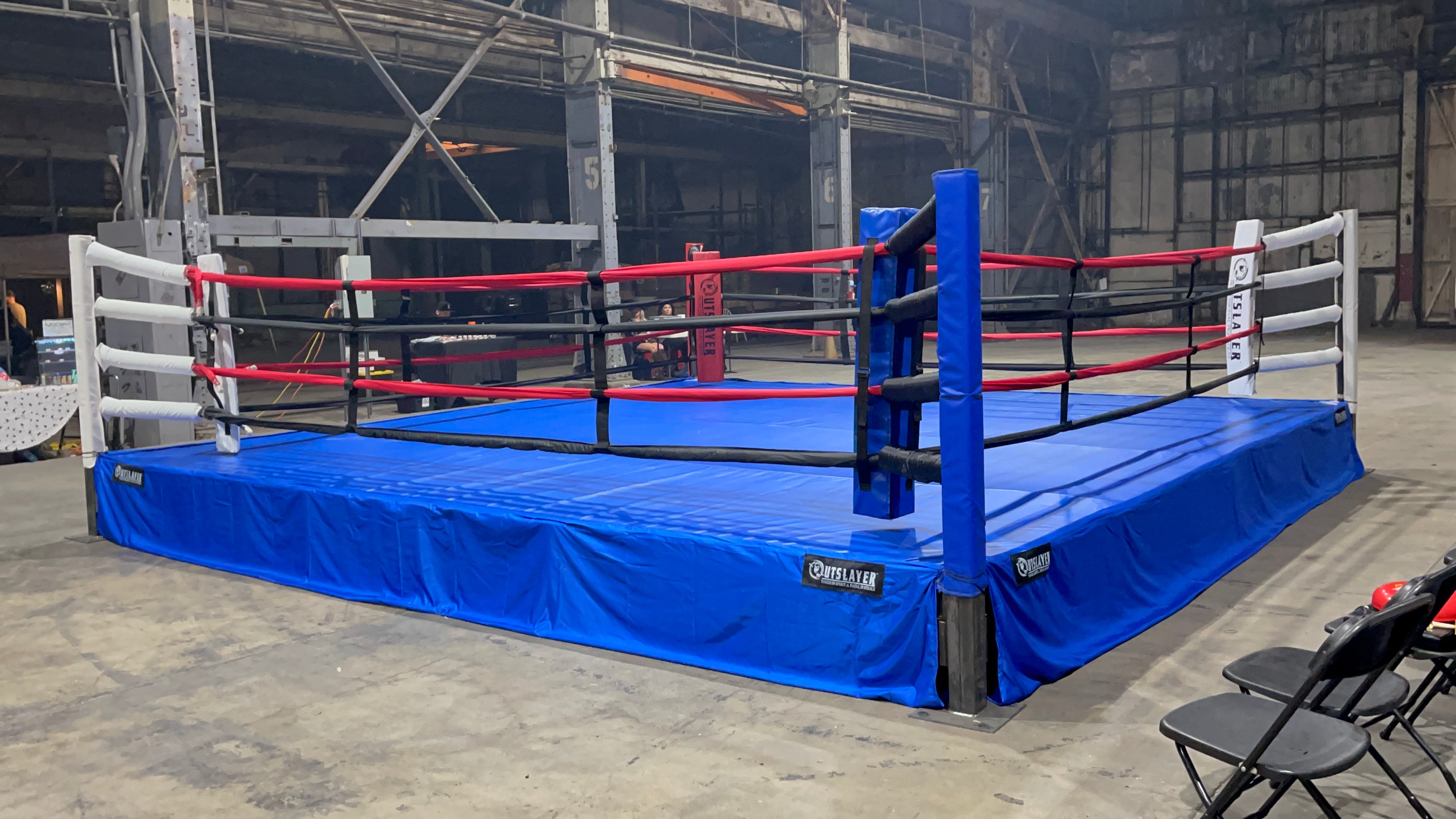 Boxing ring with blue mat and red ropes in an indoor setting