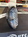 A black weighted kicking shield/pad with white 'OUTSLAYER' branding, positioned inside a boxing ring on a dark mat.
