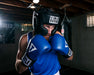 Male boxer wearing black Title headgear and blue Title boxing gloves
