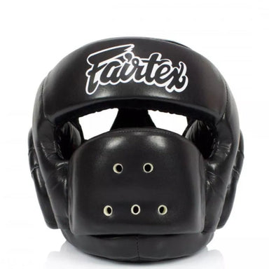 A black Fairtex boxing headguard with a white script logo on the forehead, shown against a plain white background.