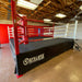 A red and black boxing ring with white ropes and a black canvas cover, labeled with 'Outslayer' brand.