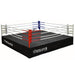 A black, elevated drop-n-lock boxing ring with red and blue corner posts and white ropes.